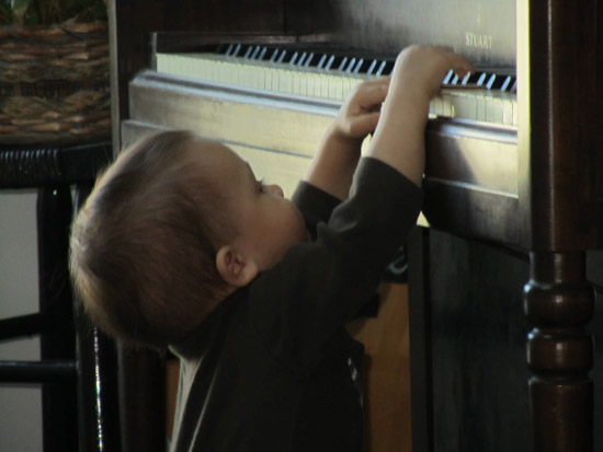 Standing up and reaching the piano on his own