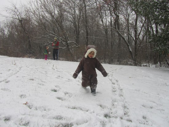 Papa and Yaya are making snowballs in the background while Adik runs around making footprints