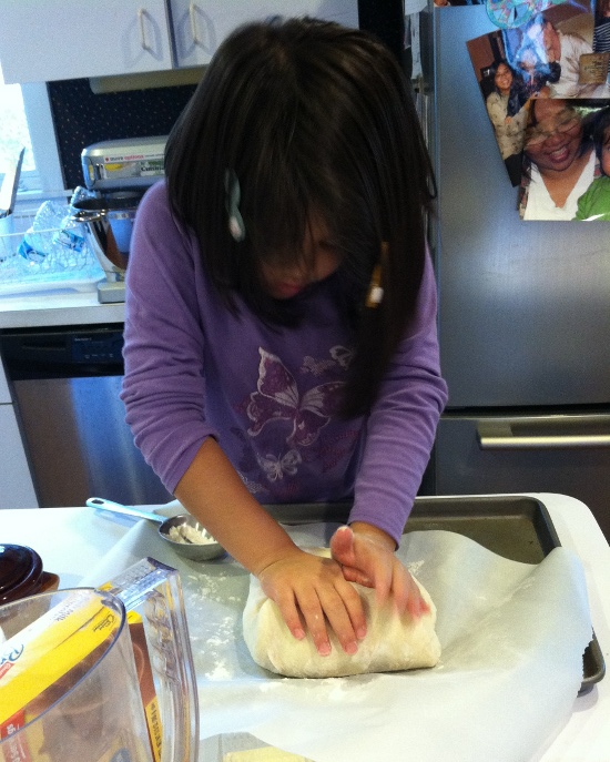 Putting her weight on her bread dough