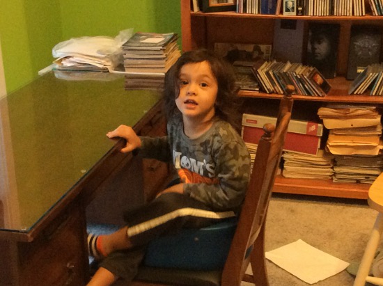 Adik sits at Granny Jean's desk on the blue bouncy chair