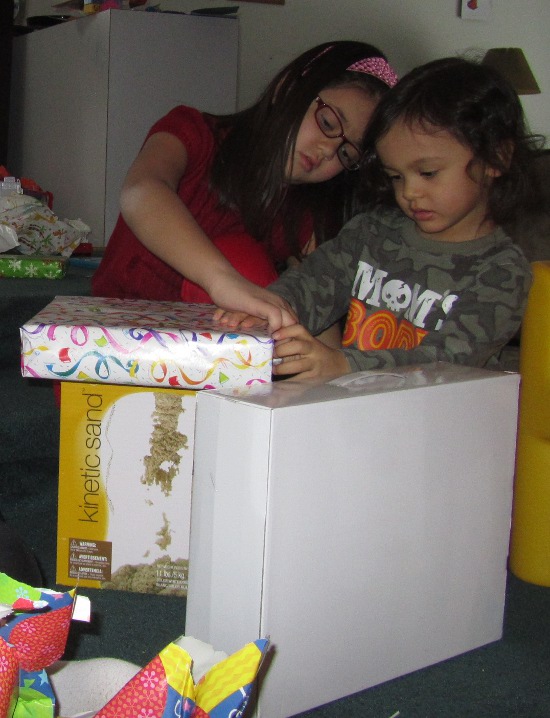 Yaya helps Adik start to rip the wrapping paper