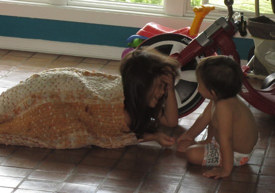 Yaya rolls herself up in the rug to hide from Adik, laughing when he finds her