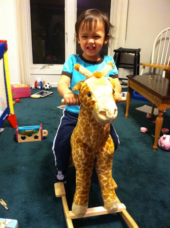 Birthday boy happily riding Rocky the Rocking Giraffe