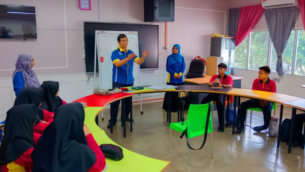 Three visiting teachers in uniform address a room full of 13 year old students